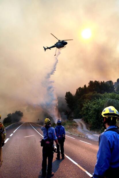 Bomberos y un helicópetro trabajando en el incendio en la C-14, entre Alcover y Vilaverd (Tarragona).