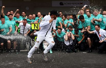 El brit&aacute;nico Lews Hamilton huye del chorro de champ&aacute;n de Nico Rosberg.