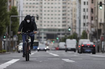 Un ciclista con mascarilla pedalea por la Gran Vía de Madrid.
