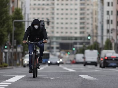 Un ciclista con mascarilla pedalea por la Gran Vía de Madrid.