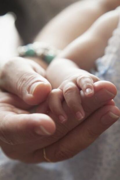 La mano de Teresa, madre de acogida de urgencia, sostiene la de la pequeña Paula.