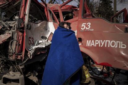 Una mujer se cubre con una manta cerca de un camión de bomberos destruido tras un ataque ruso en Mariupol. El presidente de Ucrania, Volodímir Zelenski, ha asegurado que 100.000 personas han huido por los corredores humanitarios en las dos últimas jornadas.