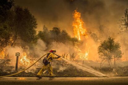 Un bombero trabaja apagando las llamas en Cloverdale Rd., cerca de Igo (California), el 28 de julio de 2018.