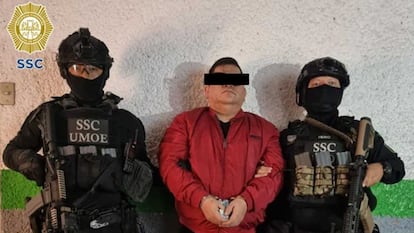 Dos elementos de la Secretaría de Seguridad Ciudadana resguardan a José Bernabé Brizuela, líder de la banda Los mezcales, tras su detención en Ciudad de México, el 18 de agosto de 2022.