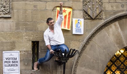 Hombre encaramado en la fachada del Ayuntamiento de Lleida levanta el puño en apoyo del referéndum.