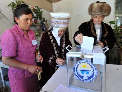 Una pareja ataviada a la manera tradicional vota en Bishkek en presencia de una interventora.