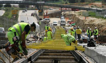 Varios operarios miden la inclinación de los raíles en las obras del metro ligero T2, en Madrid.