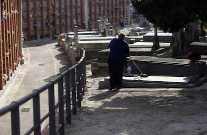 Una mujer barre la lápida en el cementerio de La Almudena de Madrid.