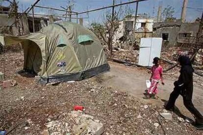 Dos niñas libanesas caminan junto a una tienda de campaña en Qana (sur de Líbano), una de las localidades más devastadas por los bombardeos.