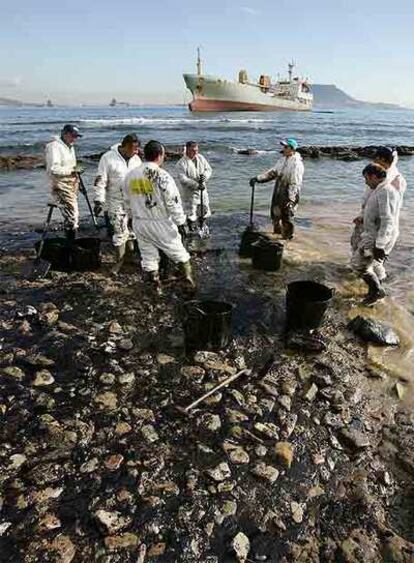 Varios operarios limpian chapapote en la playa de Algeciras.