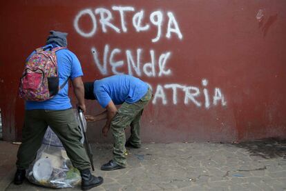 Paramilitaries limpian el suelo frente a un rayado en el que se lee: 