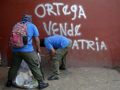 Paramilitaries limpian el suelo frente a un rayado en el que se lee: 