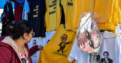 Mulher olha camiseta com a imagem do candidato Jair Bolsonaro em shopping popular no centro de São Paulo.