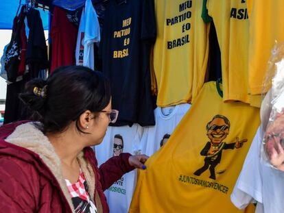 Mulher olha camiseta com a imagem do candidato Jair Bolsonaro em shopping popular no centro de São Paulo.