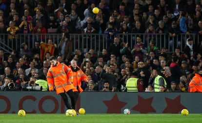 Personal del Barcelona retira las pelotas lanzadas desde la grada durante el clásico del Camp Nou.