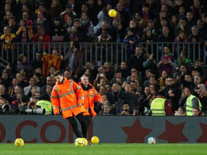Personal del Barcelona retira las pelotas lanzadas desde la grada durante el clásico del Camp Nou.
