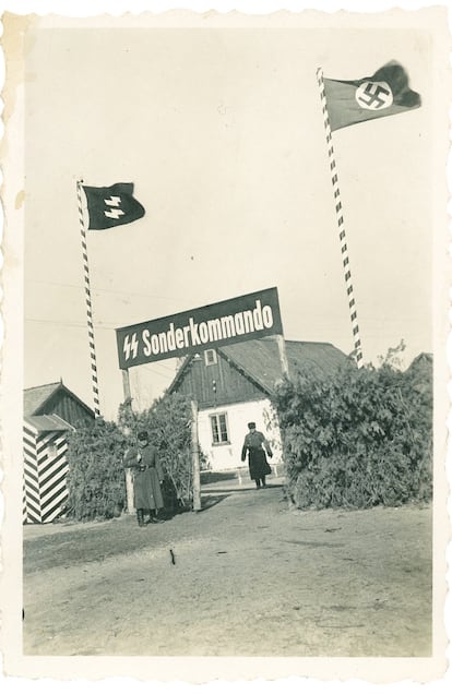 La entrada del campo de concentración de Sobibor, en la primavera de 1943. Junto a la bandera con la esvástica y al rótulo en el que se lee Sonderkommando (comando especial), se puede ver a dos guardas y una vegetación tupida sobre la valla, destinada a impedir que se viera el interior del campo. Los Sonderkommandos eran unidades de trabajo durante la Alemania nazi que estaban formados por prisioneros, seleccionados para trabajar en las cámaras de gas y en los crematorios en los campos de concentración.