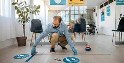 Un trabajador fija la señalética con medidas de prevención del Covid en una empresa. 