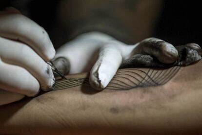 CAR34. CARACAS (VENEZUELA), 02/10/2016.- Detalle de un tatuador haciendo un tatuaje hoy, domingo 2 de octubre del 2016, en Caracas (Venezuela). Un conjunto de profesionales del "arte corporal" ofrecen hacer tatuajes a cambio de donaciones de útiles escolares para que niños de bajos recursos económicos puedan comenzar el venidero año académico, esto a través de la jornada llamada "Tatuajes x útiles" que se lleva a cabo en Caracas. EFE/MIGUEL GUTIÉRREZ