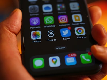 Una persona sostiene un móvil y aparecen varias 'apps' en la pantalla.