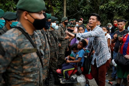 Un migrante hondureño con sus hijos frente a las fuerzas de seguridad de Guatemala.