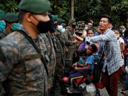 Un migrante hondureño con sus hijos frente a las fuerzas de seguridad de Guatemala.