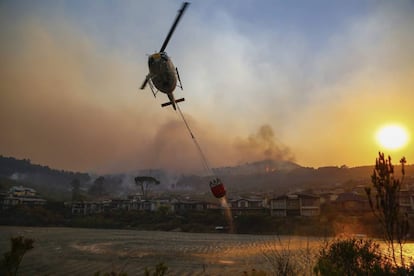 Un helicóptero recoge agua para sofocar un incendio declarado en las montañas de Heldeberg, en Somerset West (Sudáfrica).