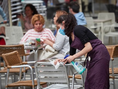 Una trabajadora desinfecta las mesas y sillas de una terraza en la plaza del Castillo de Pamplona.