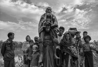 Un anciano rohingya musulmán es transportado por un hombre más joven después de cruzar la frontera de Myanmar a Bangladesh, cerca del río Naf, el 2 de noviembre de 2017 en Cox's Bazar, Bangladesh.