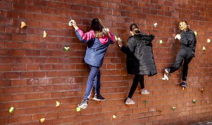 Tres niñas juegan en un rocódromo en el patio del colegio Tiana de la Riba, en Ripollet (Vallès Occidental).