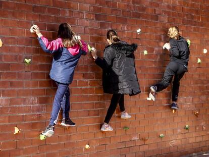 Tres niñas juegan en un rocódromo en el patio del colegio Tiana de la Riba, en Ripollet (Vallès Occidental).