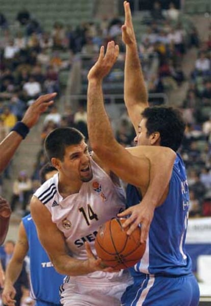 El madridista Felipe Reyes (izda.) lucha un balón ante el acoso de la defensa del Telemar brasileño.