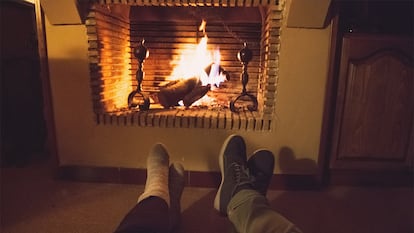 Las piernas de dos personas que están relajándose en su casa con la chimenea encendida.