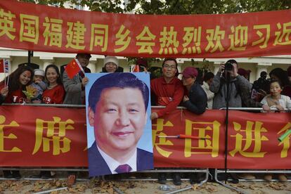 Varias personas que sostienen una fotografía del presidente chino, Xi Jinping, mientras esperan para recibirle en Londres (Reino Unido).