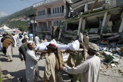 Varios habitantes de Balakot (Pakistán) portaban ayer un cadáver junto a un edificio derruido.