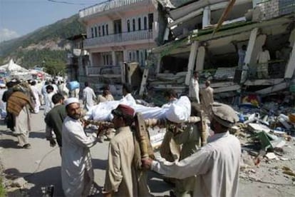 Varios habitantes de Balakot (Pakistán) portaban ayer un cadáver junto a un edificio derruido.