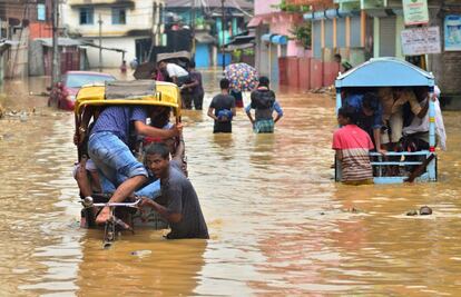 Conductores de bicitaxi transportan a la gente hacia zonas elevadas a lo largo de una calle inundada en Dimapur (India).
