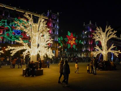 Personas caminan entre decoraciones festivas en el Zócalo de la capital mexicana, en diciembre de 2021.