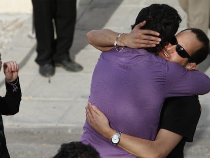 Un amigo da el pésame en el tanatorio de Lorca al hijo sordomudo de una de las fallecidas, con camisa negra.