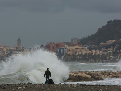 Una persona pasea este martes por la playa de Pedregalejo, en Málaga capital, cuyo paseo marítimo ha resultado afectado por el agua que ha dañado varios chiringuitos de la zona en el temporal.