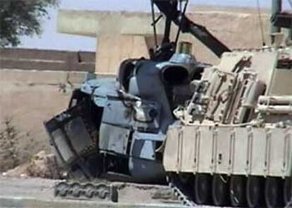 Un tanque estadounidense pasa junto al helicóptero derribado en Nayaf.