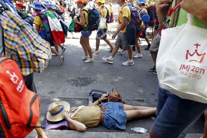 Miles de peregrinos llegaron a Cuatro Vientos caminando y ayer domingo se marchaban de la misma manera. Tras pasar una noche de acampada a la intemperie y una semana en colegio o polideportivos, muchos jóvenes están acostumbrados a descansar donde pueden. Una joven hace una parada en el camino de vuelta a casa mientras los demás caminan por su lado.