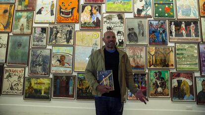 El artista Peter Doig posa ante un mural de carteles pertenecientes a la exposici&oacute;n &#039;Studiofilmclub&#039; del Centro de Arte Contempor&aacute;neo de M&aacute;laga.