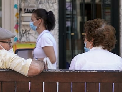 Una pareja de ancianos con mascarilla, sentada en un banco de Madrid el pasado julio.