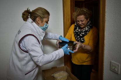 Inma, una vecina de la localidad navarra de Villava, entrega unos recipientes con ensaladilla rusa y arroz con leche a una voluntaria para transportarlo a la base de Protección Civil, donde han montado un puesto de avituallamiento para los servicios de emergencias que operan durante el estado de alarma.