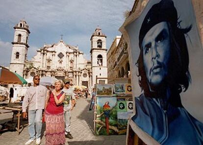 Unos turistas pasan por delante de un cartel de Ernesto <i>Che</i> Guevara en La Habana.