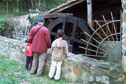 Unos visitantes observan la gran rueda de cangilones en el ecomuseo de la sal.