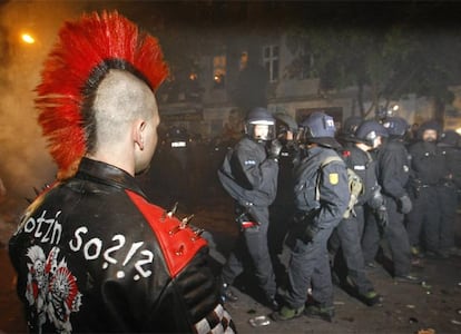 Un manifestante observa a un grupo de policías durante los violentos altercados que han tenido lugar durante una protesta de grupos de ultraizquierda.