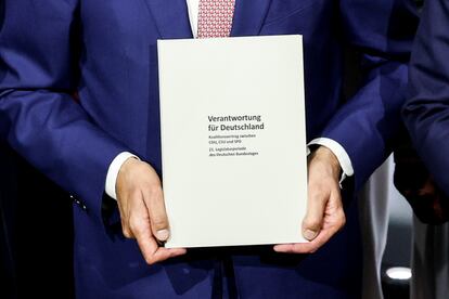 Las manos del líder de la CDU, Friedrich Merz, sostienen el acuerdo de coalición con el SPD durante su presentación este lunes. 
