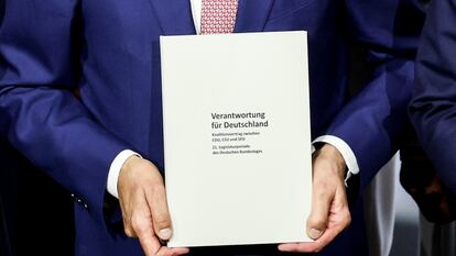 Las manos del líder de la CDU, Friedrich Merz, sostienen el acuerdo de coalición con el SPD durante su presentación este lunes.